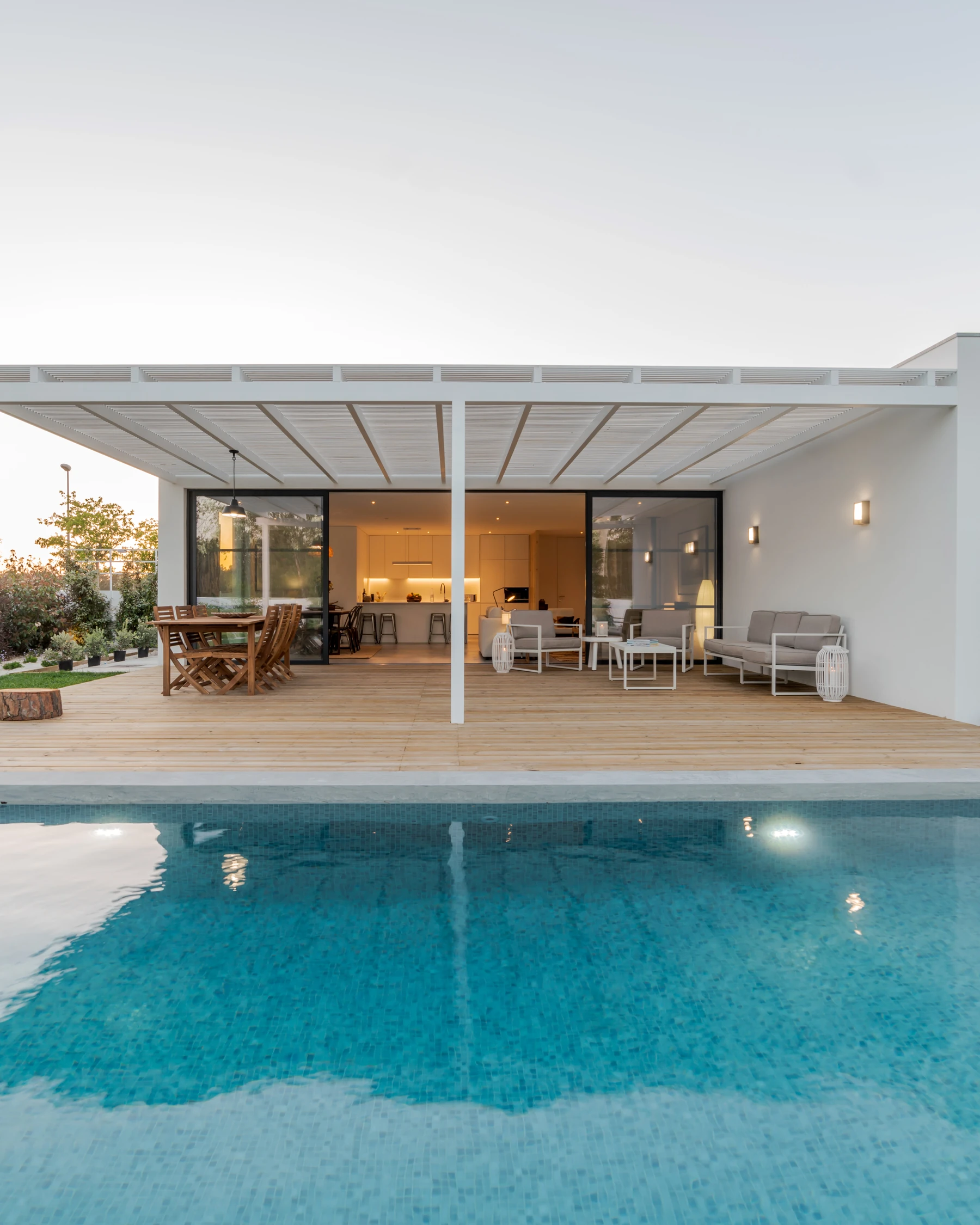 A swimming pool beside a modern open-plan home
