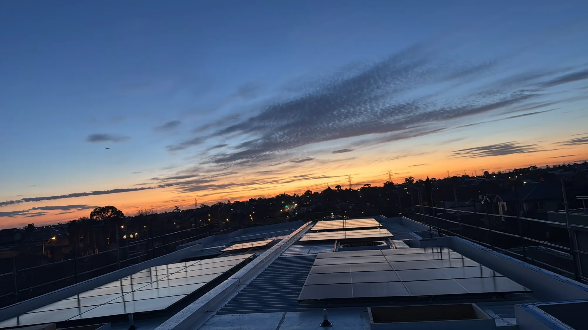 A completed Lumenx rooftop solar installation at dusk, overlooking an Australian suburb